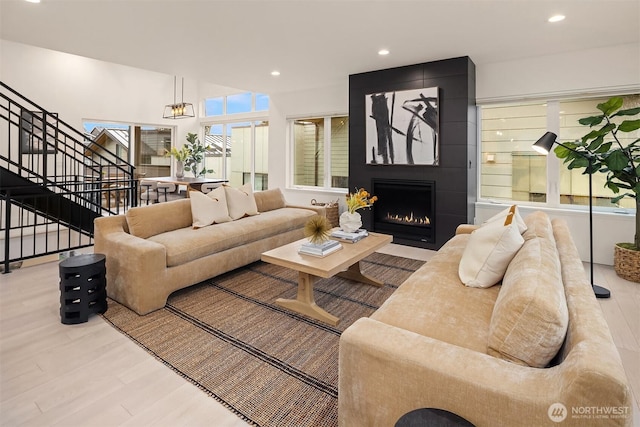 living room featuring recessed lighting, a large fireplace, stairway, and wood finished floors