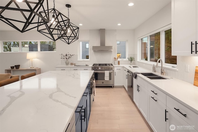 kitchen with a healthy amount of sunlight, wall chimney exhaust hood, stainless steel appliances, and a sink