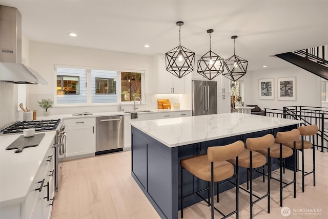 kitchen featuring premium appliances, a center island, a sink, wall chimney range hood, and a kitchen bar