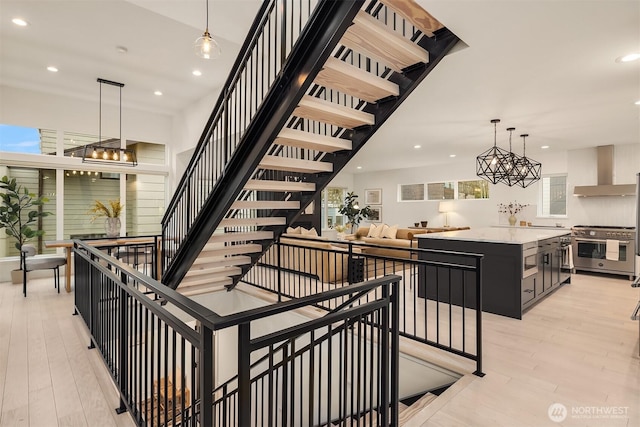 stairs featuring recessed lighting, a notable chandelier, and wood finished floors