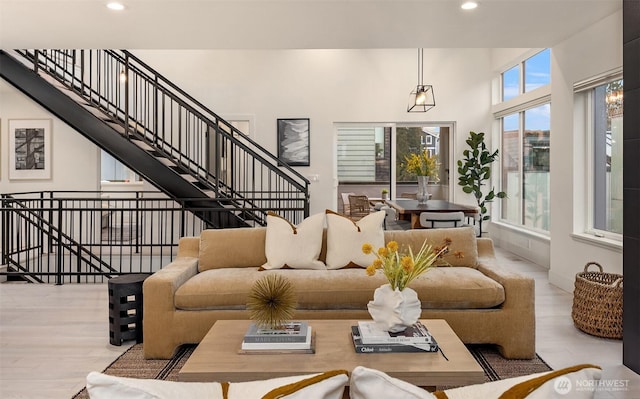 living area with stairs, a high ceiling, wood finished floors, and recessed lighting