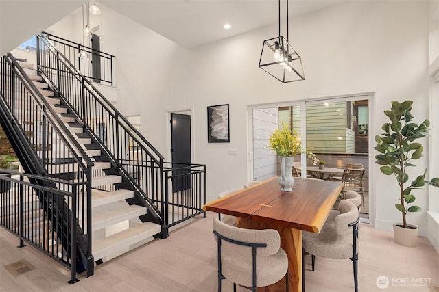 dining room featuring stairs, a high ceiling, and light wood-type flooring