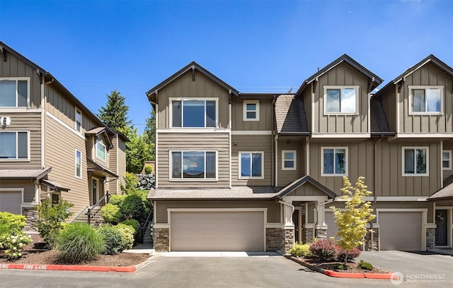 townhome / multi-family property featuring driveway, a shingled roof, stone siding, an attached garage, and board and batten siding