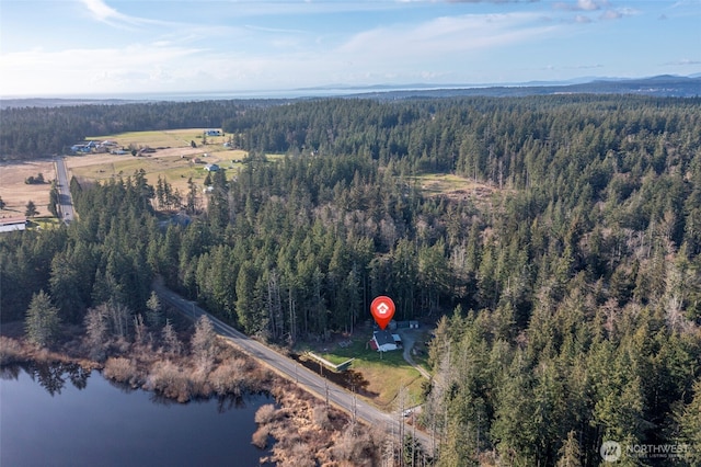 birds eye view of property featuring a water view and a wooded view