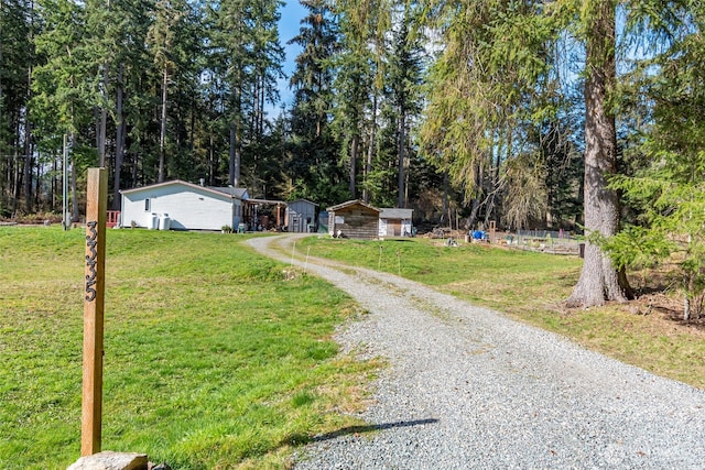 view of front of home with gravel driveway, an outbuilding, and a front yard