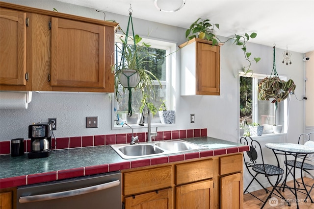 kitchen featuring a sink, tile countertops, brown cabinetry, and dishwasher