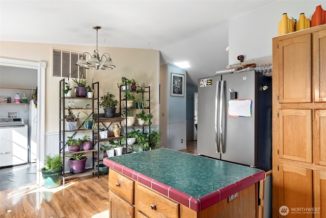 kitchen featuring a center island, washer / clothes dryer, light wood-style floors, freestanding refrigerator, and vaulted ceiling