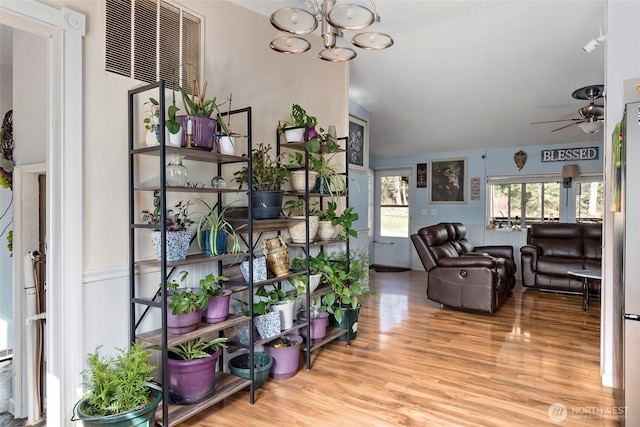 interior space featuring ceiling fan with notable chandelier, vaulted ceiling, and wood finished floors