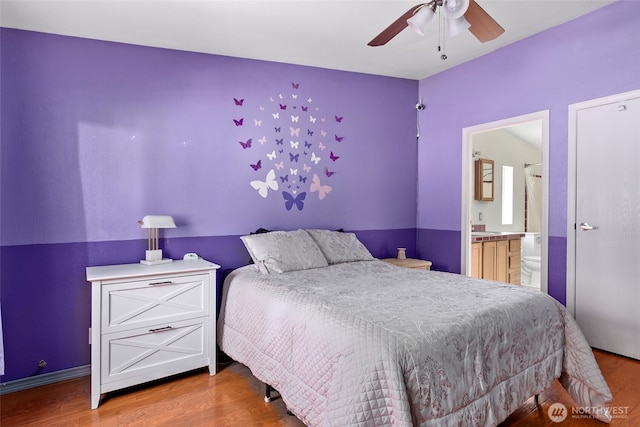 bedroom with a ceiling fan, wood finished floors, and ensuite bathroom