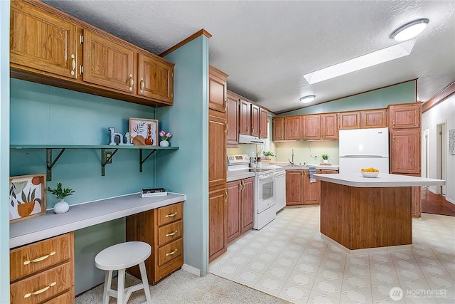 kitchen with brown cabinets, light floors, light countertops, vaulted ceiling with skylight, and white appliances