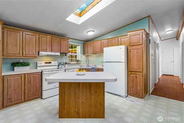 kitchen featuring white appliances, light floors, light countertops, under cabinet range hood, and a sink