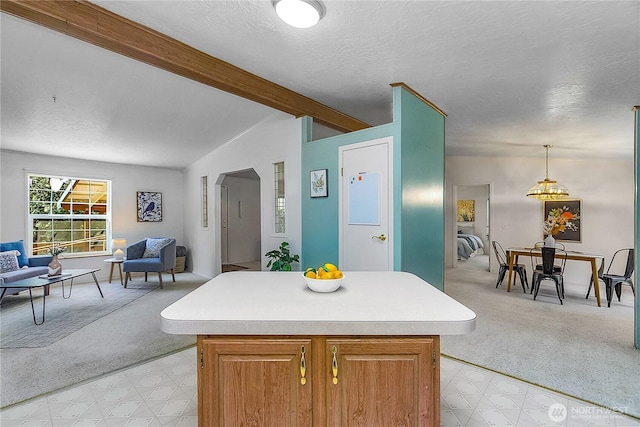 kitchen featuring open floor plan, light countertops, lofted ceiling with beams, and light carpet