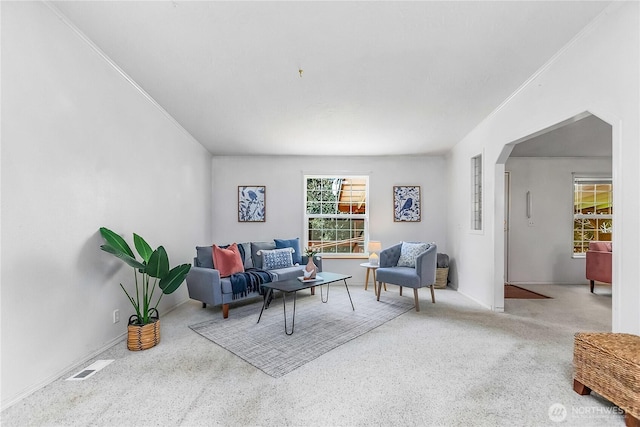 living room with ornamental molding, arched walkways, and visible vents