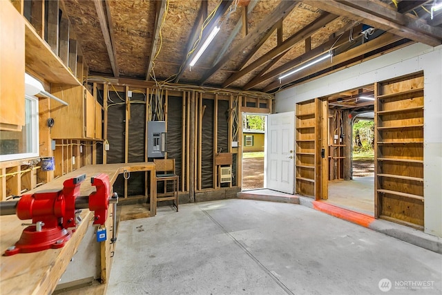 misc room featuring unfinished concrete flooring and electric panel