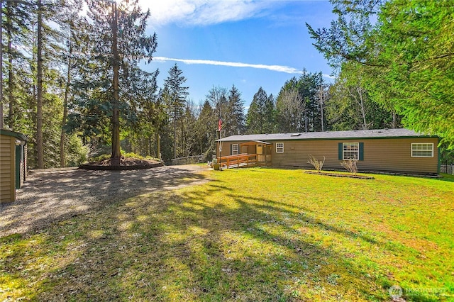 view of yard featuring a wooded view and a wooden deck