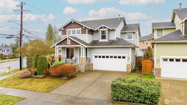 craftsman-style house featuring a porch, a shingled roof, concrete driveway, an attached garage, and a gate