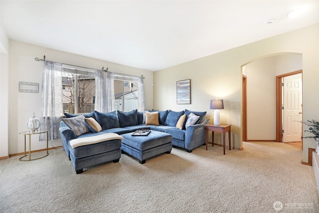 carpeted living room with arched walkways and baseboards