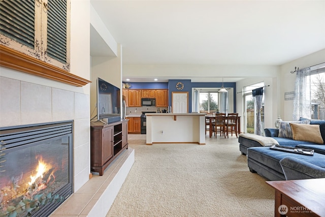 living area with light carpet, a tiled fireplace, and recessed lighting