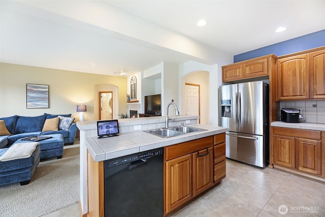 kitchen featuring black dishwasher, tile countertops, open floor plan, stainless steel refrigerator with ice dispenser, and a sink