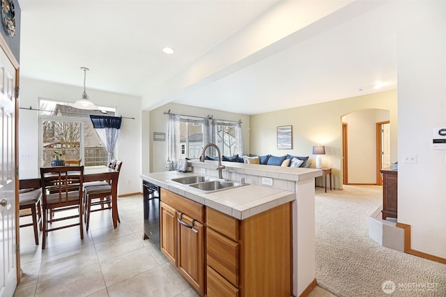 kitchen featuring black dishwasher, tile counters, arched walkways, brown cabinets, and a sink