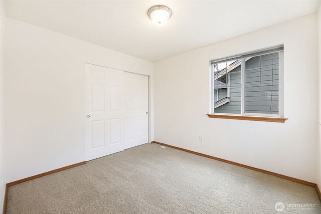 unfurnished bedroom featuring carpet, visible vents, baseboards, and a closet