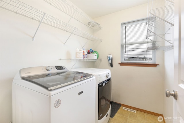 clothes washing area featuring laundry area, washer and clothes dryer, visible vents, and baseboards