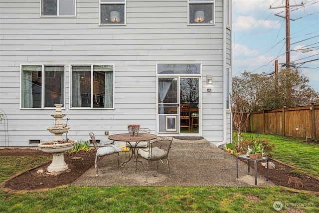 rear view of property with crawl space, a patio area, fence, and a lawn