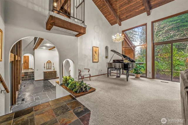 interior space featuring arched walkways, lofted ceiling with beams, wood ceiling, and an inviting chandelier