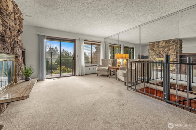 sitting room featuring a textured ceiling, a stone fireplace, and carpet flooring