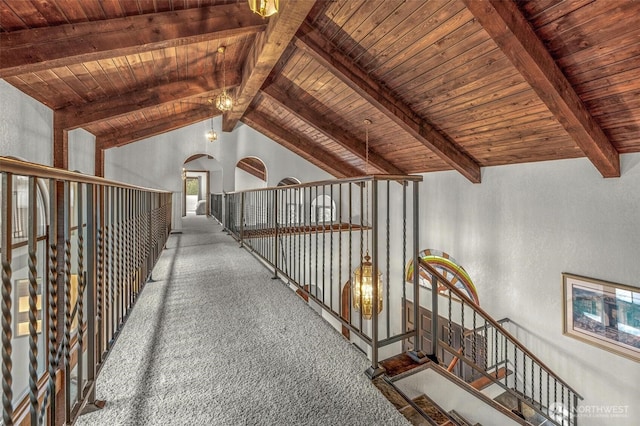 hallway featuring lofted ceiling with beams, wooden ceiling, carpet flooring, and a textured wall