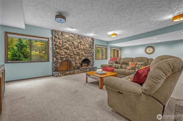 living room with a textured ceiling, a stone fireplace, carpet flooring, and baseboards