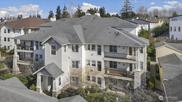 rear view of house with roof with shingles and a residential view