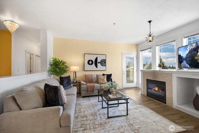 living area with a tile fireplace, wood finished floors, and an inviting chandelier