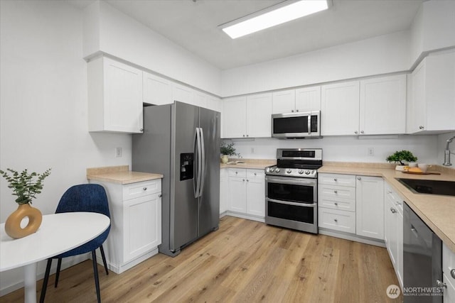 kitchen with light countertops, appliances with stainless steel finishes, a sink, and white cabinetry