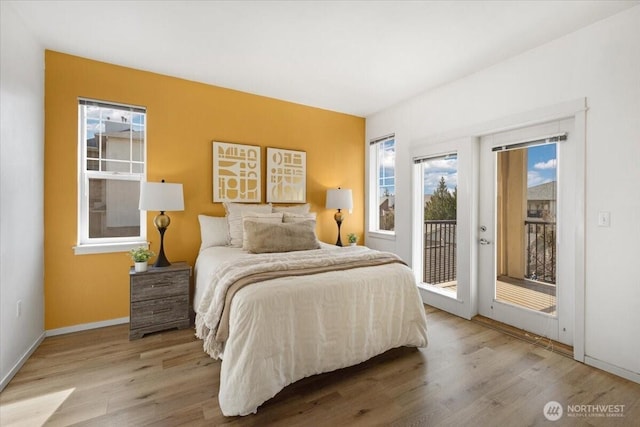 bedroom with baseboards, wood finished floors, and access to exterior