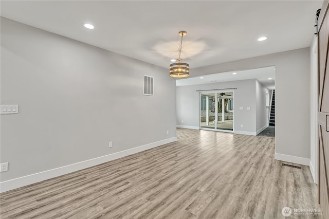 empty room featuring light wood finished floors, baseboards, visible vents, and recessed lighting