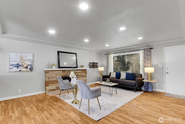 living room with recessed lighting, baseboards, a textured ceiling, and light wood finished floors