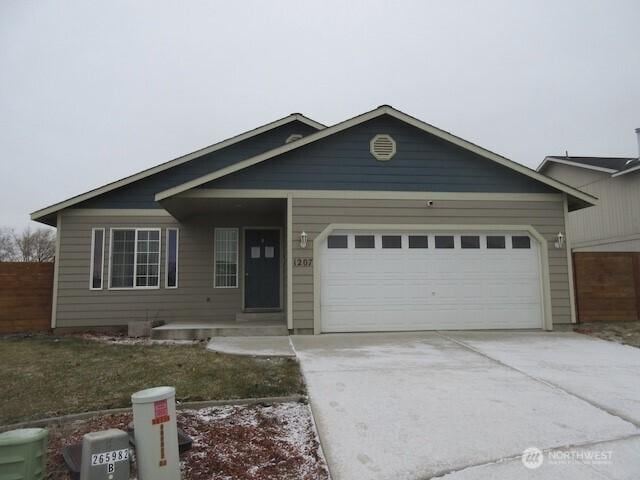 ranch-style house featuring an attached garage, driveway, and fence