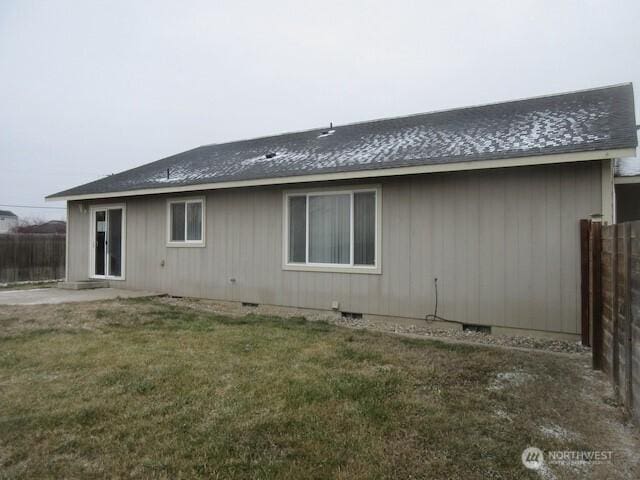 rear view of property with crawl space, fence, and a yard