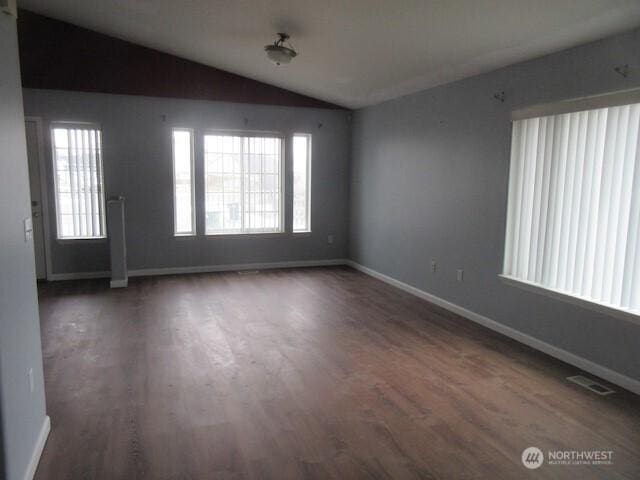 spare room with lofted ceiling, plenty of natural light, wood finished floors, and visible vents