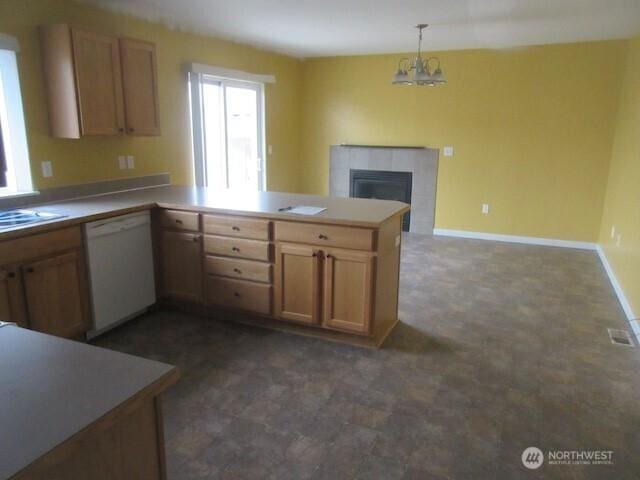 kitchen with baseboards, a tile fireplace, a peninsula, white dishwasher, and pendant lighting