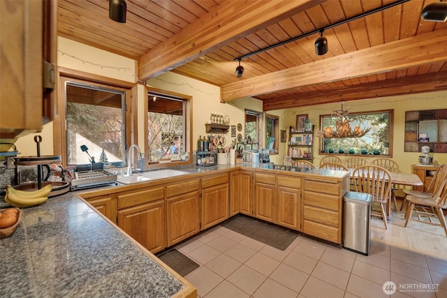 kitchen with light tile patterned floors, wooden ceiling, beamed ceiling, a peninsula, and a sink