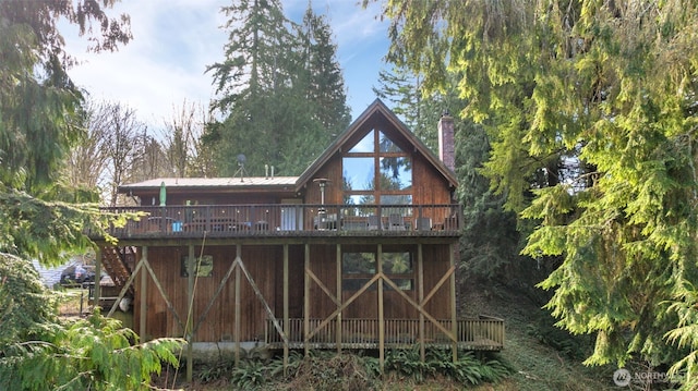 rear view of property featuring metal roof, a chimney, and a deck