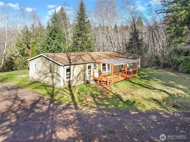 view of front of house with a front yard and a view of trees