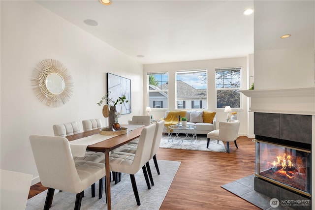 dining room with recessed lighting, baseboards, wood finished floors, and a tile fireplace