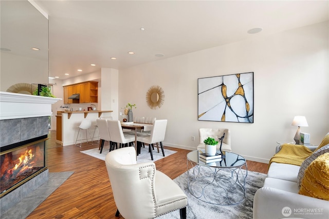 living room with baseboards, a fireplace, wood finished floors, and recessed lighting