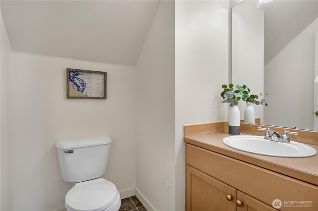 bathroom with baseboards, toilet, tile patterned floors, vaulted ceiling, and vanity