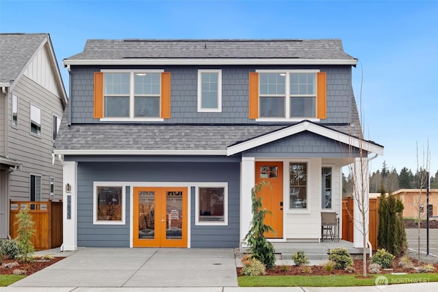 view of front of house featuring a shingled roof, french doors, covered porch, and fence