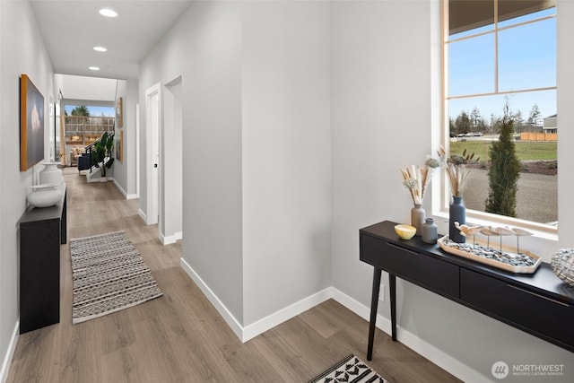 hall featuring light wood-style flooring, baseboards, and recessed lighting