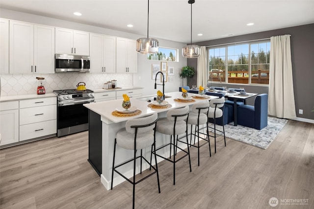 kitchen featuring decorative backsplash, light wood-style flooring, stainless steel appliances, light countertops, and a sink